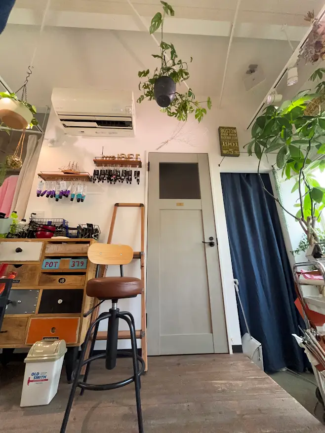136ism の店内。グレーのドアと観葉植物、木製のチェスト